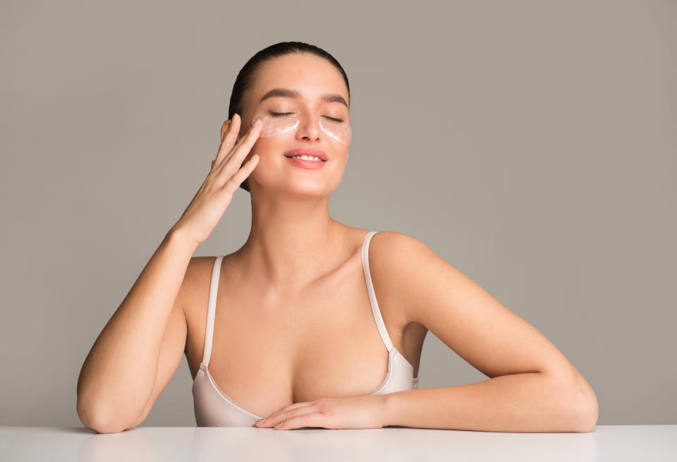 Skin beauty. Woman with collagen pads under eyes over grey studio background