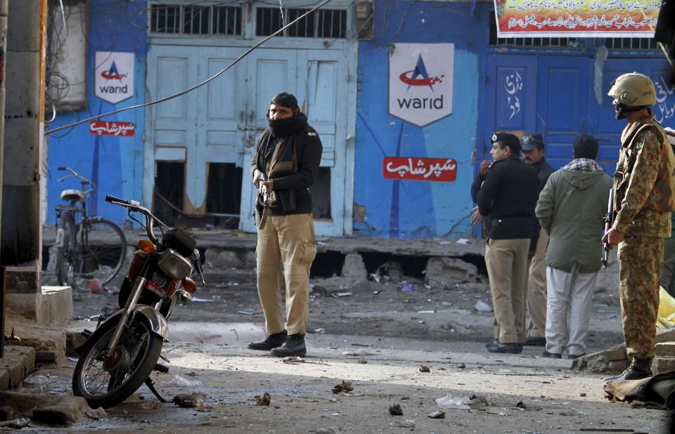 A Pakistani police officer and army soldier secure a street close to the site of a suicide bombing in Rawalpindi, Pakistan on Monday, Jan. 20, 2014. A suicide bomber blew himself up not far from Pakistan's military headquarters Monday, killing at least a dozen people a day after a Taliban bombing inside an army compound in the northwest of the country killed many troops, officials and militants said. (AP Photo/Anjum Naveed)