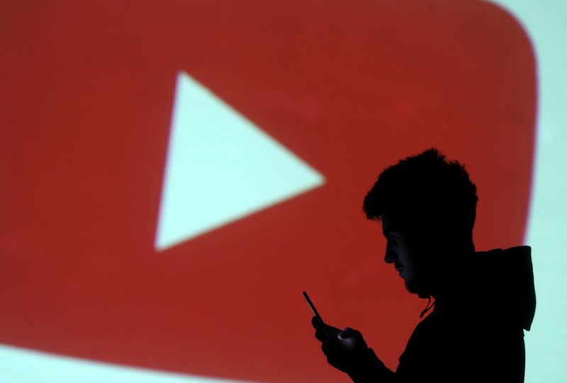 FILE PHOTO: A silhouette of a mobile user is seen next to a screen projection of Youtube logo in this picture illustration