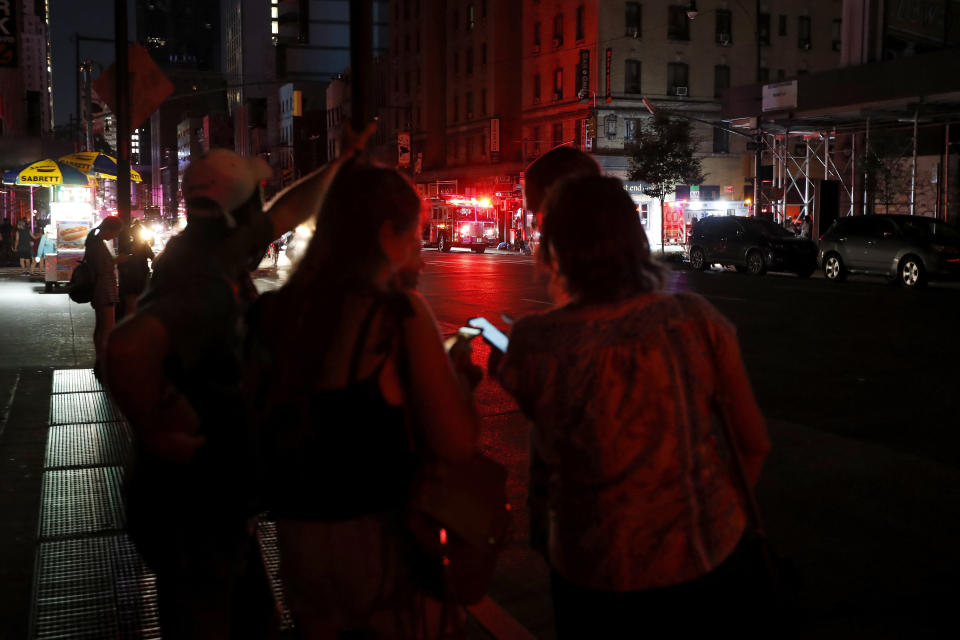 Pedestrians looks at their cellphones during a power outage in midtown Manhattan, Saturday, July 13, 2019, in New York. Authorities were scrambling to restore electricity to Manhattan following a power outage that knocked out Times Square's towering electronic screens and darkened marquees in the theater district and left businesses without electricity, elevators stuck and subway cars stalled. (AP Photo/Michael Owens)