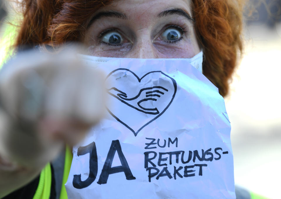 25 June 2020, Hessen, Frankfurt/Main: During a demonstration in front of Lufthansa headquarters at Frankfurt Airport, a Lufthansa flight attendant wears a mouth guard with the words "Yes to the rescue package". The company's shareholders decide at the Extraordinary General Meeting whether or not they want the state to become a shareholder for about 300 million euros. Photo: Arne Dedert/dpa (Photo by Arne Dedert/picture alliance via Getty Images)