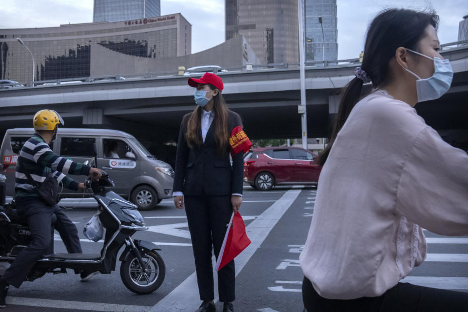 A crossing guard wearing a face mask to protect against COVID-19 stands at an intersection in the central business district in Beijing, Thursday, Sept. 16, 2021. China on Thursday reported several dozen additional locally-transmitted cases of coronavirus as it works to contain an outbreak in the eastern province of Fujian. (AP Photo/Mark Schiefelbein)