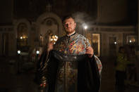 A priest delivers a religious service inside the Transfiguration of Jesus Orthodox Cathedral during a blackout caused by recent Russian rocket attacks, in Kyiv, Ukraine, Saturday, Dec. 3, 2022. A top Orthodox priest in Ukraine's capital says he supports the efforts of President Volodymyr Zelenskyy's government and counter-intelligence agency to end Russian spying and meddling in Ukrainian politics through a Moscow-affiliated church. (AP Photo/Efrem Lukatsky)
