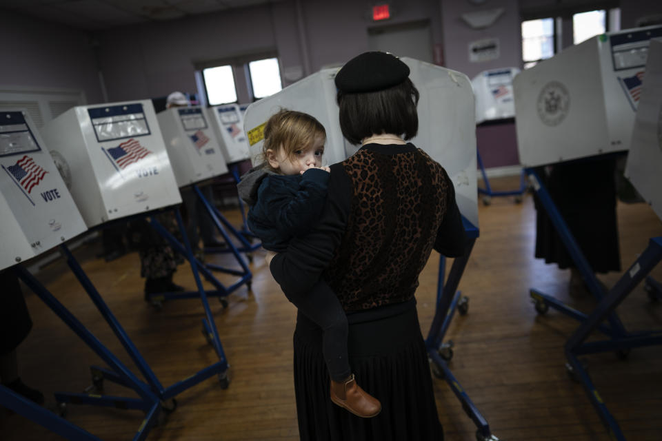 A member of the Orthodox Jewish community carries her child as she fills out ballot papers at a polling center on, Tuesday, Nov. 8, 2022, in the Brooklyn borough of New York. (AP Photo/Wong Maye-E)