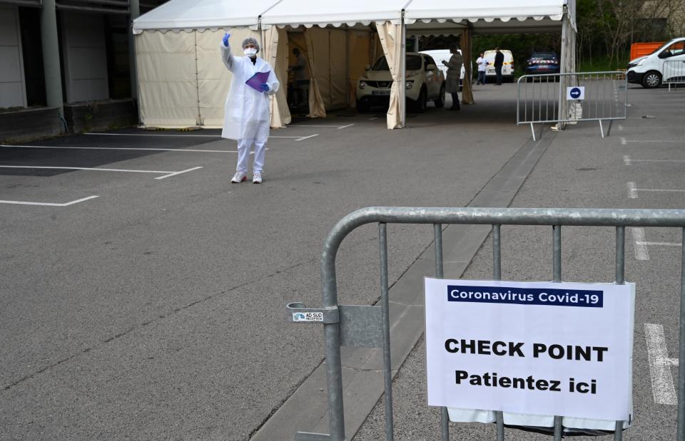 A biologist gestures at motorists waiting to have samples taken at a  COVID-19 screening-drive in Montpellier, south-western France, on March 27, 2020, as the country is under lockdown to stop the spread of the Covid-19 pandemic caused by the novel coronavirus. (Photo by Pascal GUYOT / AFP) (Photo by PASCAL GUYOT/AFP via Getty Images)