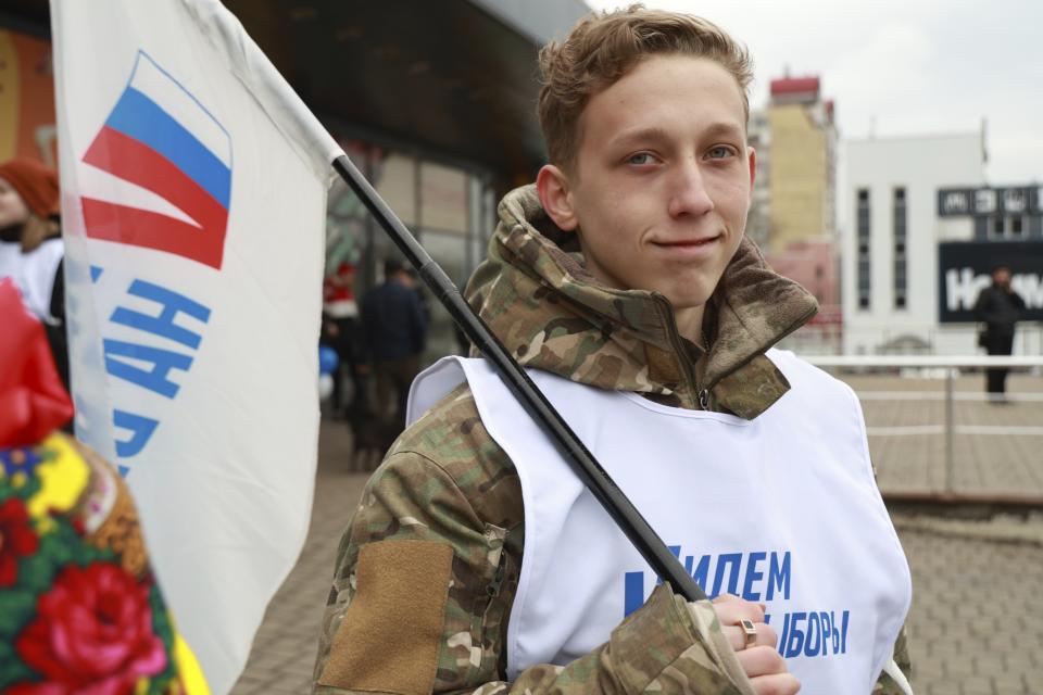 A volunteer holds a flag reading "let's go to the elections" promoting the upcoming presidential election in a street in Donetsk, the capital of Russian-controlled Donetsk region, eastern Ukraine, on Thursday, March 14, 2024. Russian President Vladimir Putin Thursday called on people in Ukraine's occupied regions to vote, telling them and Russians that participation in the elections is "manifestation of patriotic feeling," Presidential elections are scheduled in Russia for March 17. (AP Photo)