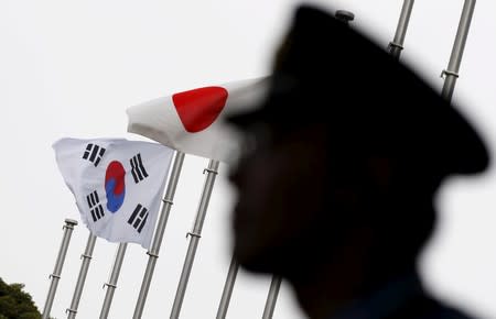 Police officer stands guard near Japan and South Korea national flags at hotel, where South Korean embassy in Japan is holding the reception to mark the 50th anniversary of normalisation of ties between Seoul and Tokyo in Tokyo