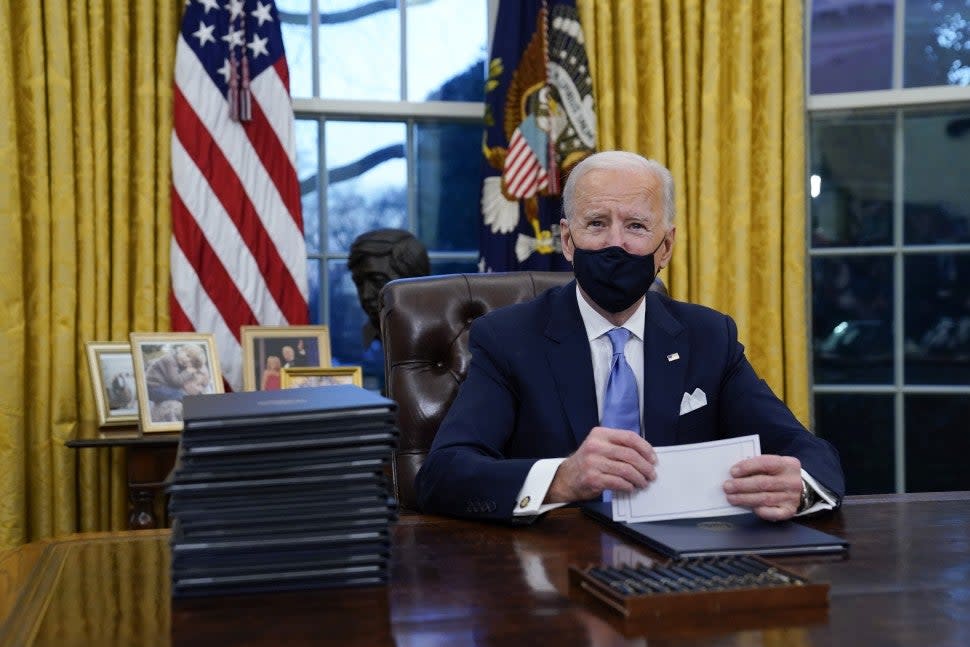 President Joe Biden pauses as he signs his first executive orders in the Oval Office of the White House on Wednesday, Jan. 20, 2021.