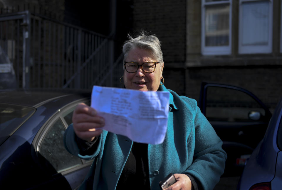 The Rev. April Keech, an Anglican priest, who organizes food deliveries to old and vulnerable people, holds a shopping list in London, Saturday, March 28, 2020. Keech and her team of volunteers have spent the past two weeks buying groceries, filling prescriptions and making deliveries to residents in east London who are at risk of serious illness or death from the COVID-19 disease. (AP Photo/Alberto Pezzali)