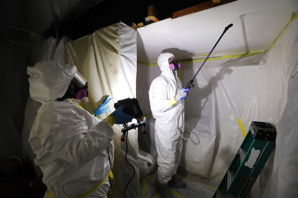 File - In this Oct. 18, 2017, file photo, Asbestos Removal Technologies Inc., job superintendent Ryan Laitila, right, sprays amended water as job forman Megan Eberhart holds a light during asbestos abatement in Howell, Mich. A federal appeals court says the Trump administration unlawfully excluded millions of tons of some of the most dangerous materials in public use from a safety review. (AP Photo/Paul Sancya, File)