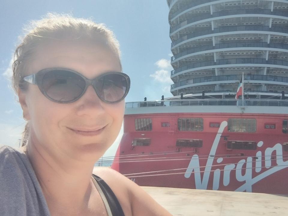 Woman wearing black sunglasses taking a selfie with Virgin Voyages cruise