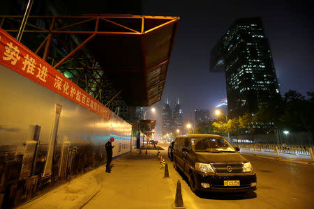 A construction security personnel stands next to a poster bearing a picture of Beijing's central business district area, China April 16, 2017. REUTERS/Jason Lee