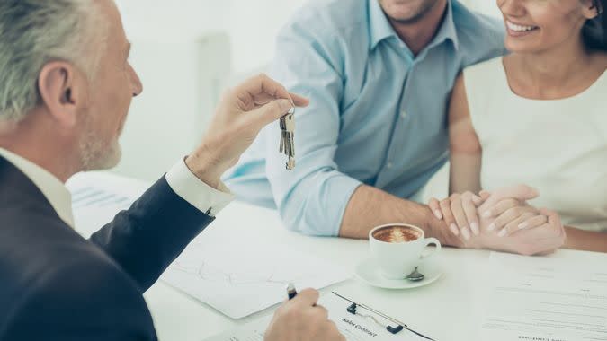 Close up of real estate agent giving keys to couple of customers.