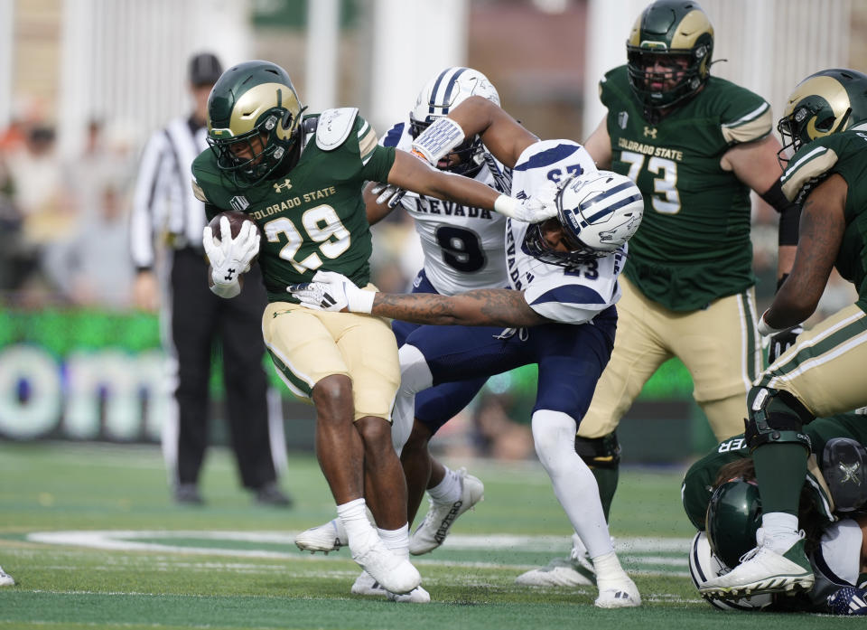 Colorado State running back Justin Marshall, left, is pulled down after short gain by Nevada defensive backs Tre Weed and Richard Toney Jr., right, n the first half of an NCAA college football game Saturday, Nov. 18, 2023, in Fort Collins, Colo. (AP Photo/David Zalubowski)