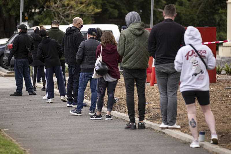 People are seen queueing up for a COVID-19 test at a pop-up test site at the St Kilda Town Hall, in Melbourne.