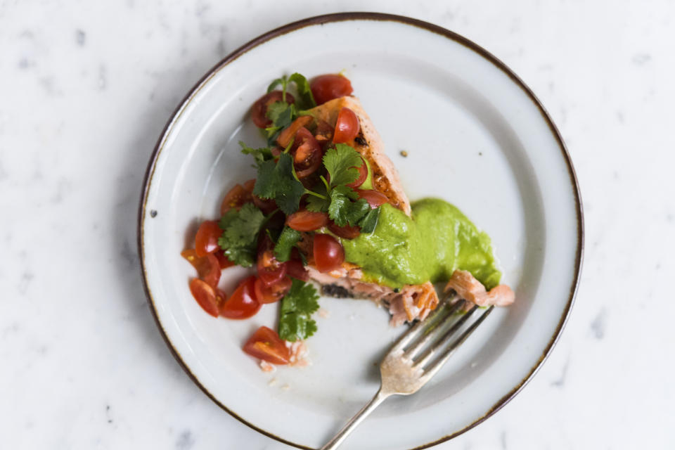 This image released by Milk Street shows a recipe for salmon with avocado sauce and tomato-cilantro salsa. (Milk Street via AP)