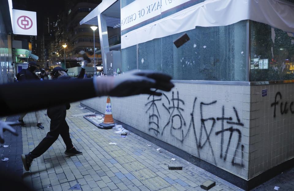 Protestors vandalize a subway entrance in Hong Kong, Sunday, Oct.13, 2019. Protesters changed tactics and popped up in small groups in multiple locations across the city Sunday rather than gather in one large demonstration, pursued by police who swooped in to make muscular arrests. (AP Photo/Kin Cheung)