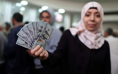 A Palestinian Hamas-hired employee displays US dollar notes after receiving her salary, in the southern Gaza Strip November 9, 2018. REUTERS/Ibraheem Abu Mustafa