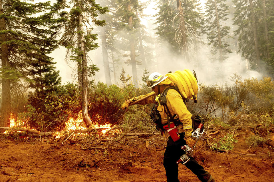 FILE - In this Sept. 14, 2020 file photo Cal Fire Battalion Chief Craig Newell carries a hose while battling the North Complex Fire in Plumas National Forest, Calif. U.S. wildfire managers are considering shifting from seasonal firefighting crews to full-time, year-round crews to deal with what has become a year-round wildfire season and to make wildland firefighting jobs more attractive by increasing pay and benefits. U.S. Forest Service Deputy Chief Christopher French, testifying before the U.S. Senate Committee on Energy and Natural Resources, said Thursday, June 24, 2021 agencies will seek to convert at least 1,000 seasonal wildland firefighters to permanent, full-time, year-round workers. (AP Photo/Noah Berger,File)