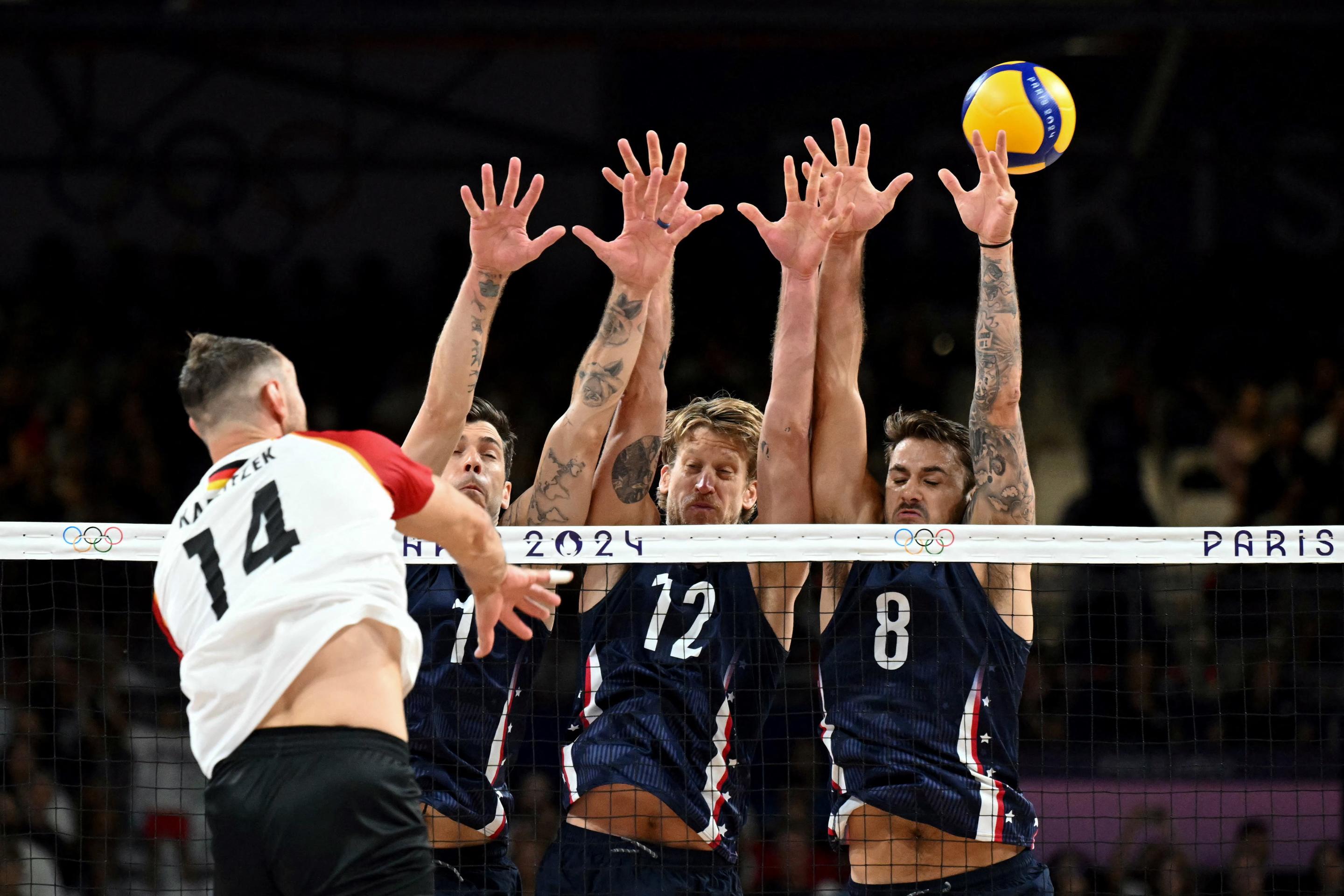 (Back L to R) US' #01 Matthew Anderson, US' #12 Maxwell Holt and US' #08 Torey DeFalco miss to block the ball from Germany's #14 Moritz Karlitzek during the men's preliminary round volleyball match between USA and Germany during the Paris 2024 Olympic Games at the South Paris Arena 1 in Paris on July 30, 2024. (Natalia Kolesnikova/AFP via Getty Images)