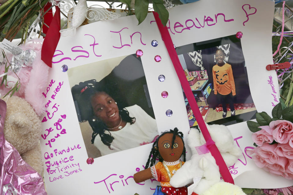 Photos adorn a large memorial to Trinity Love Jones, the 9-year-old girl whose body was found in a duffel bag along a suburban Los Angeles equestrian trail, in Hacienda Heights, Calif., Monday, March 11, 2019. Two people have been detained in connection with the case. The discovery happened last week. (AP Photo/Reed Saxon)