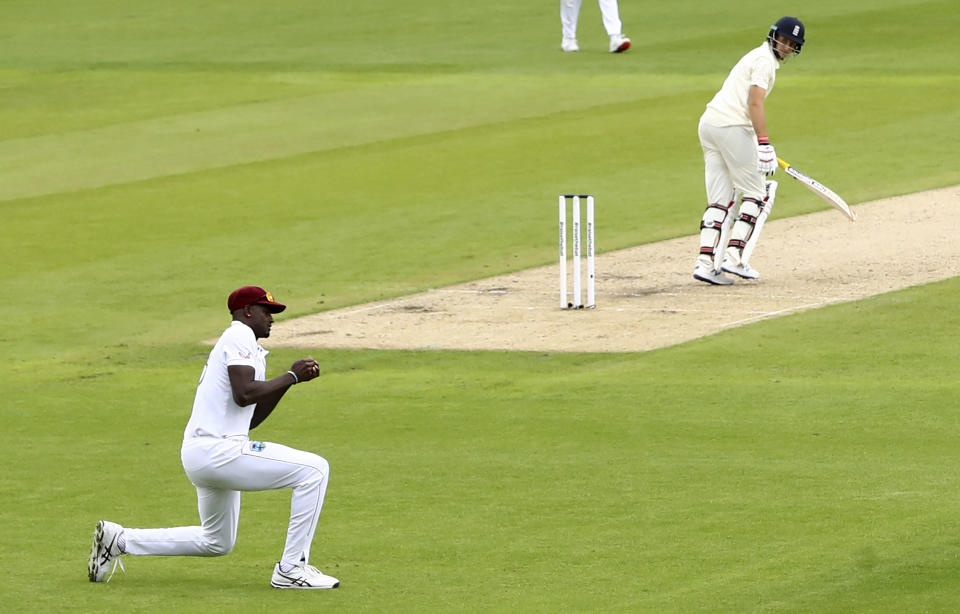 West Indies' captain Jason Holder, left, takes the catch to dismiss England's captain Joe Root, right, during the first day of the second cricket Test match between England and West Indies at Old Trafford in Manchester, England, Thursday, July 16, 2020. (Michael Steele/Pool via AP)