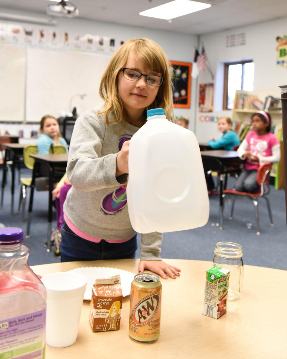 Second-grader Johanna Shaw picks an indented milk jug to recycle during class on Feb. 24, 2015.