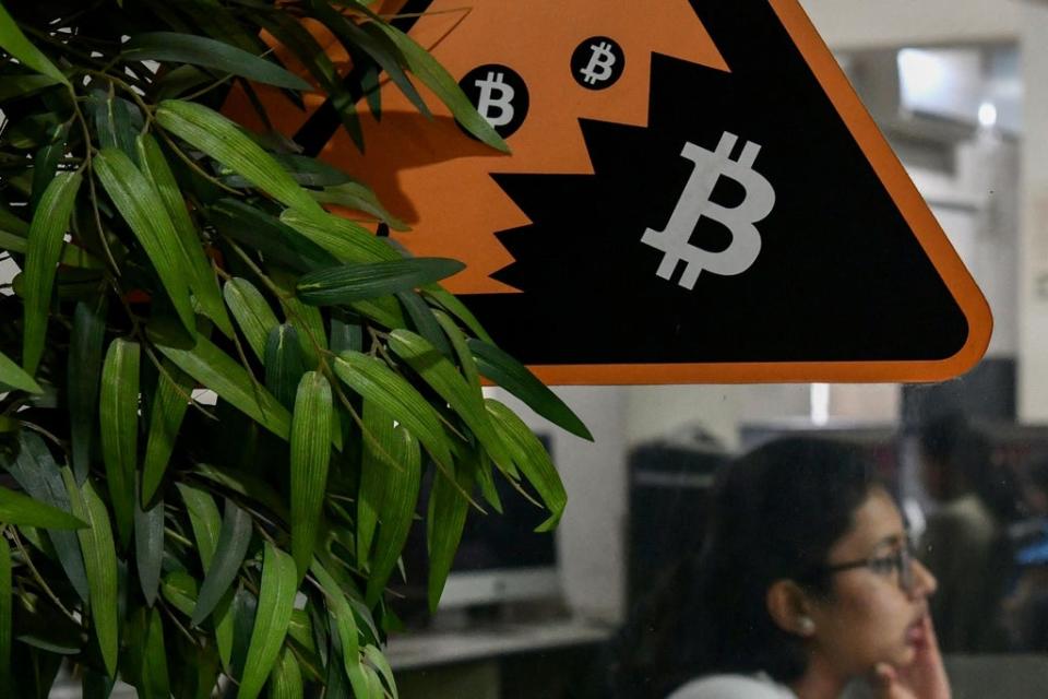 In this picture taken on November 23, 2021 an employee works on her workstation on the backdrop of the cryptocurrency symbol of Bitcoin pasted on a glass door of a private office in Bengaluru  (AFP via Getty Images)