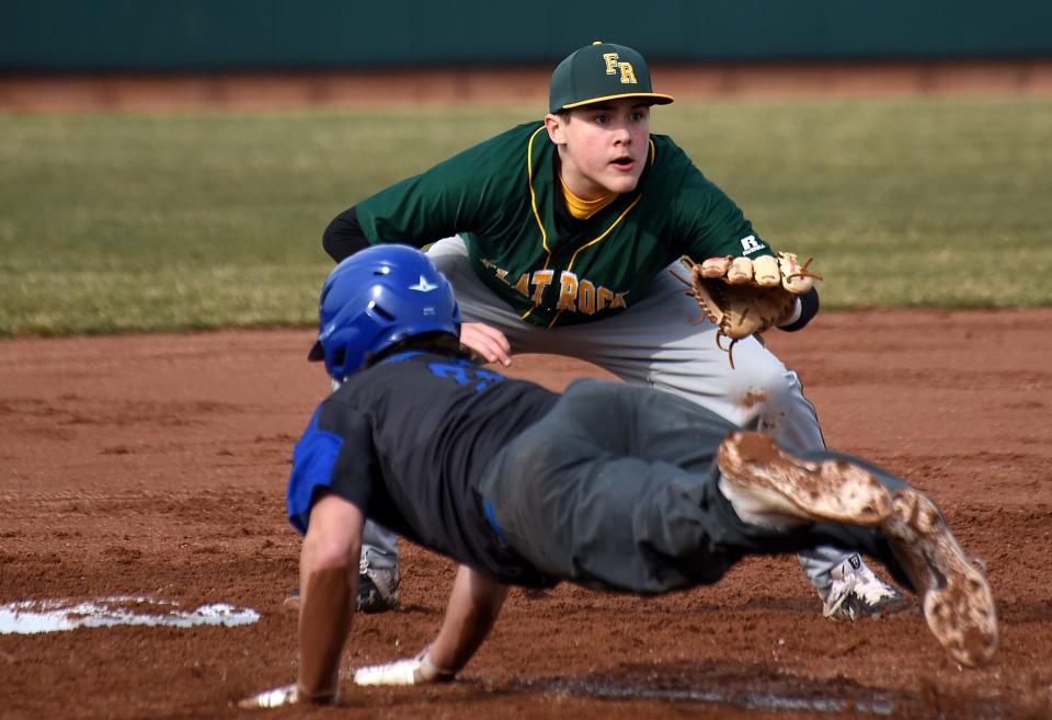 Flat Rock third baseman Bryce Elliott waits for the ball as Thomas Hamilton of Gibraltar Carlson dives back.