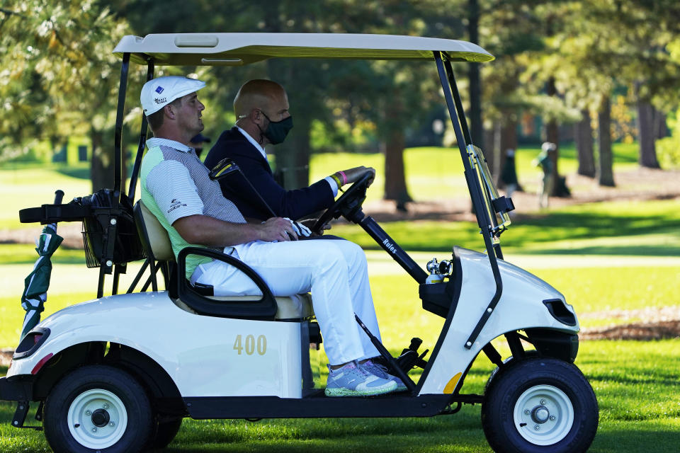 Bryson DeChambeau gets a ride back to the third tee box to hit again after his ball was lost during the second round of the Masters golf tournament Friday, Nov. 13, 2020, in Augusta, Ga. (AP Photo/David J. Phillip)