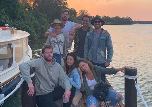 A photo of Liam Hemsworth, Elsa Pataky and Chris Hemsworth and friends posing on a jetty next to a boat.