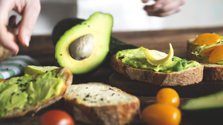 person  making avocado sandwich