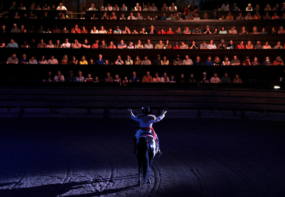 A performer spreads his arms out to those seated in The South as he divides the room of diners at Dolly Parton's Stampede into factions of North and South which will cheer on their teams as they compete in various events like barrel riding, chicken chasing, and pig races in Branson, Mo. on July 17, 2021.<span class="copyright">Jessica Rinaldi—The Boston Globe/Getty Images</span>