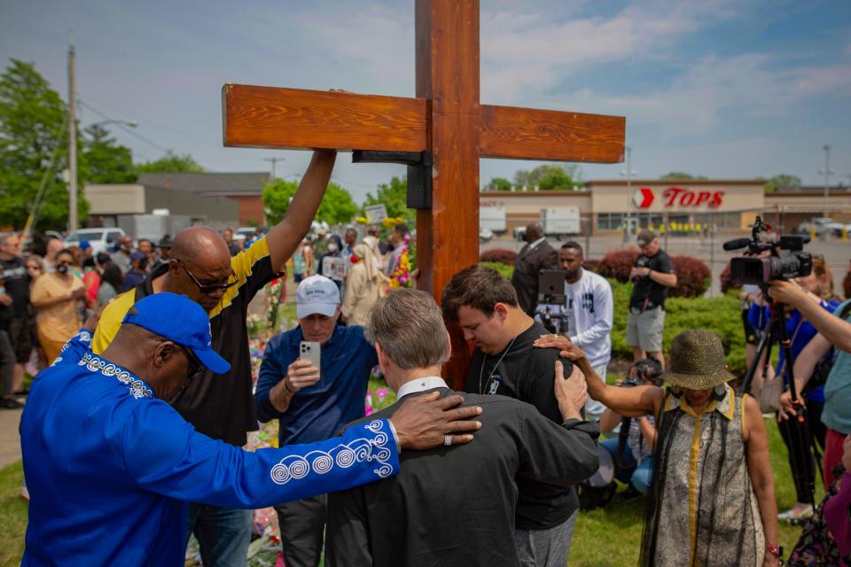 A group prays May 21, 2022, at the site of a memorial for the victims of a mass shooting at Tops Friendly Market in Buffalo, New York. Ten people were killed and three wounded May 14 when a white gunman opened fire on shoppers and employees at the store.