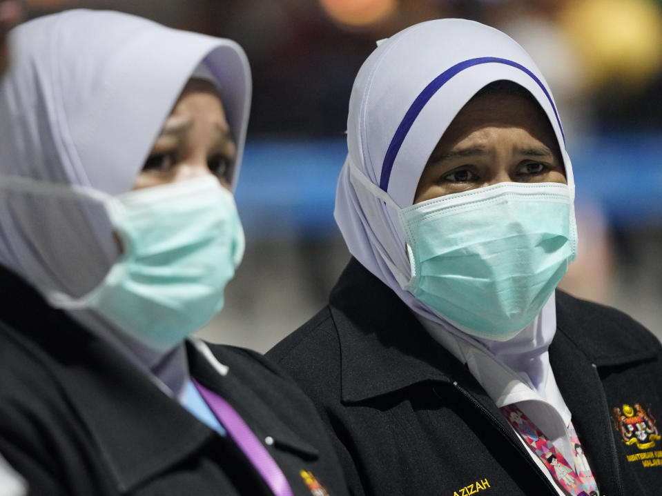 Health officials wear face masks at an inspection site at the Kuala Lumpur International Airport in Sepang, Malaysia, Tuesday, Jan. 21, 2020. Countries both in the Asia-Pacific and elsewhere have initiated body temperature checks at airports, railway stations and along highways in hopes of catching those at risk of carrying a new coronavirus that has sickened more than 200 people in China. (AP Photo/Vincent Thian)