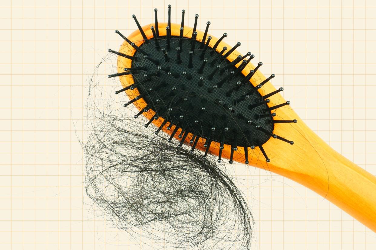 A brush next to a clump of hair on a designed background
