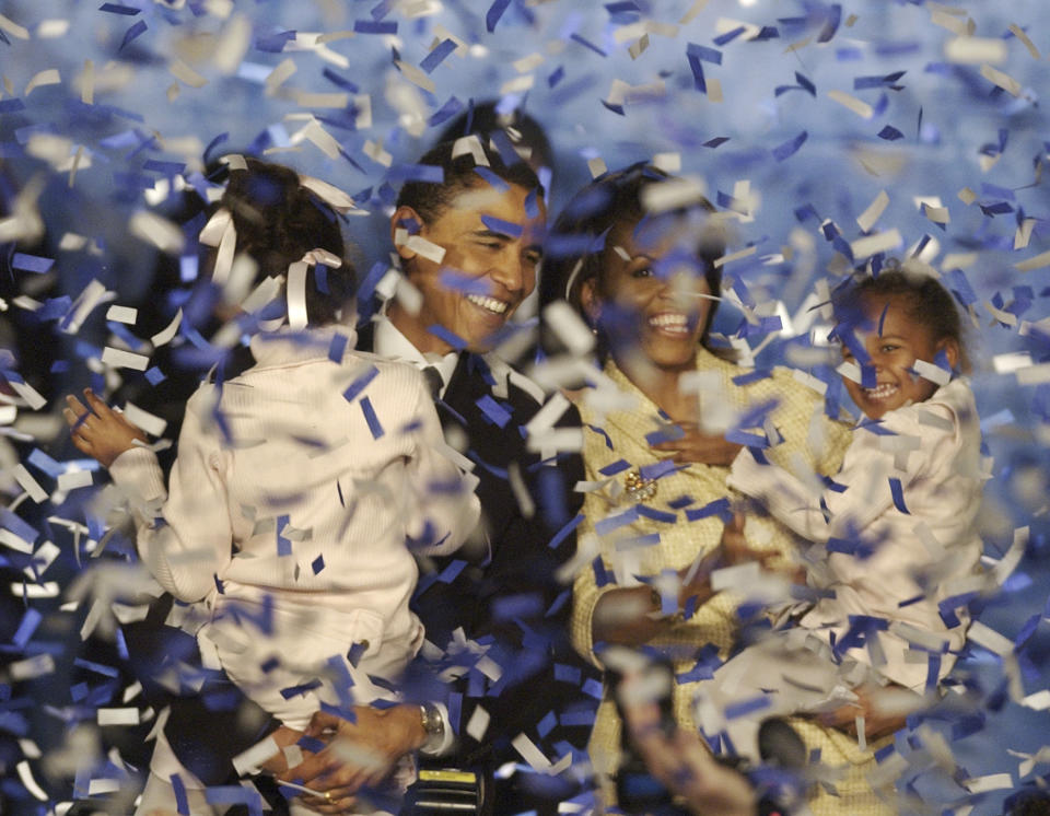 FILE - In this. Nov. 2, 2004 file photo, Illinois Sen.-elect Barack Obama, holds his daughter Malia, and his wife Michelle, holds their daughter Sasha, and are covered in confetti after Obama delivered his acceptance speech in Chicago. Obama was only the fifth black U.S. Senator to be elected in history. (AP Photo/M. Spencer Green, File)