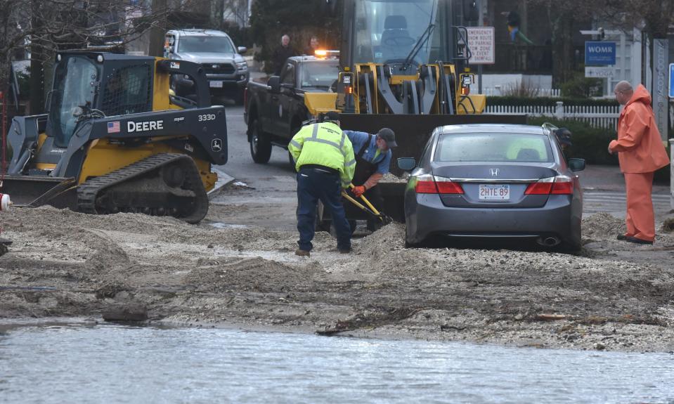 Town public works crews dig out a stranded car on Commercial Street in the east end of Provincetown on Friday, when high tide and high winds led to flooding in parts of the town.