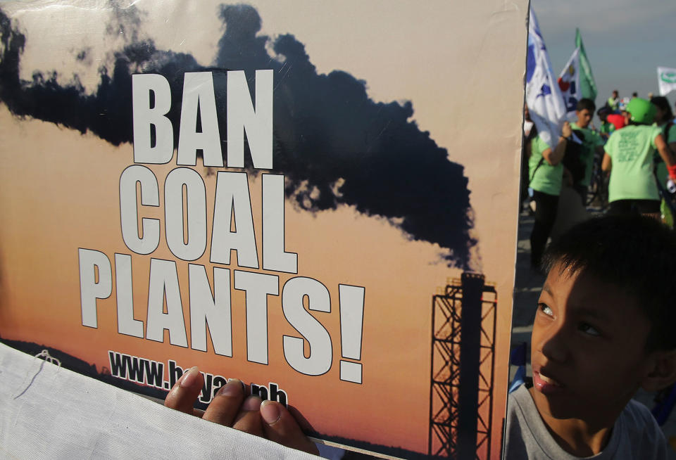 <p>A Filipino boy passes by a slogan during a rally in Manila, Philippines on Sunday, Dec. 13, 2015 to criticize the agreement reached during the United Nations conference on climate change, Conference of Parties 21 (COP21) in Paris. Nearly 200 nations adopted the first global pact to fight climate change on Saturday, calling on the world to collectively cut and then eliminate greenhouse gas pollution but imposing no sanctions on countries that don’t. (AP Photo/Aaron Favila) </p>