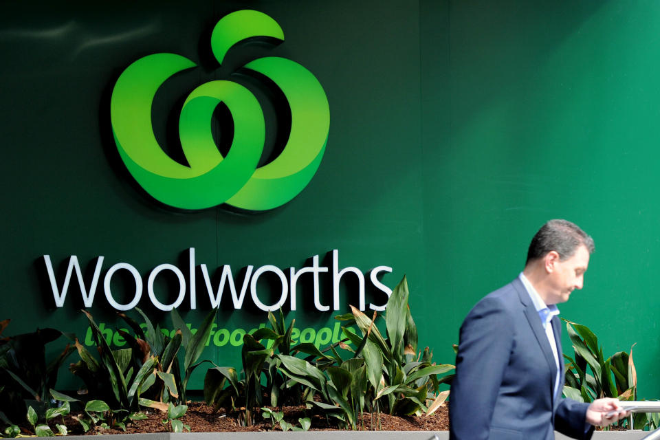 A man walks past a Woolworths sign.