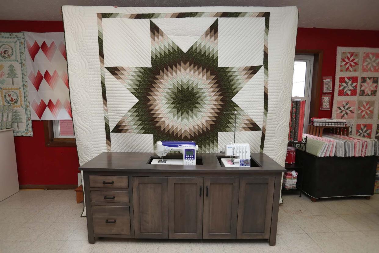 This locally made hand-sewn quilt with a Lone Star design, is one of many quilts for sale along with fabrics and quilting patterns at Lone Star Quilt Shop in Mount Hope. The sewing cabinet, displaying a Juki sewing machine and a Juki serger, is also locally made.