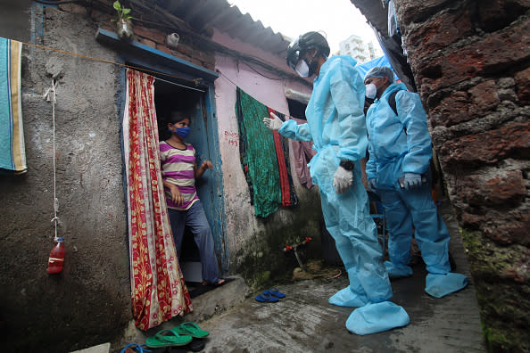 A healthcare worker wearing smart helmet checks the temperature of a resident during a medical check-up at a slum in Mumbai, India.