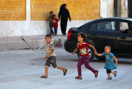 Children react as they run after hearing the sound of a Syrian fighter jet hovering over Idlib city, Syria July 18, 2015. REUTERS/Ammar Abdullah