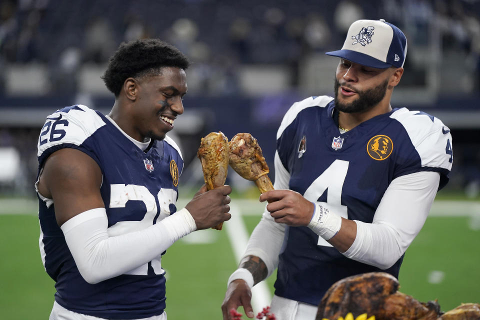 El cornerback DaRon Bland (izquierda) y el quarterback Dak Prescott, de los Cowboys de Dallas, comen pavo para celebrar la victoria sobre los Commanders de Washington en el Día de Acción de Gracias, el jueves 23 de noviembre de 2023 (AP Foto/Sam Hodde)