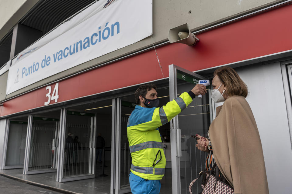 A worker from the Madrid Medical Emergency Service takes the temperature of a woman who is going to be vaccinated against COVID-19 at the Wanda Metropolitano stadium, Madrid, Spain, March 30, 2021. Spain is trying to stamp out a new wave of COVID-19 among its youth thanks to a robust vaccination program that is widely supported. Spain like the rest of the European Union got off to a slow start to compared to the United States and Britain when the first vaccines were released. But it has quickly made up ground once deliveries by drug makers started flowing. (AP Photo/Olmo Calvo)