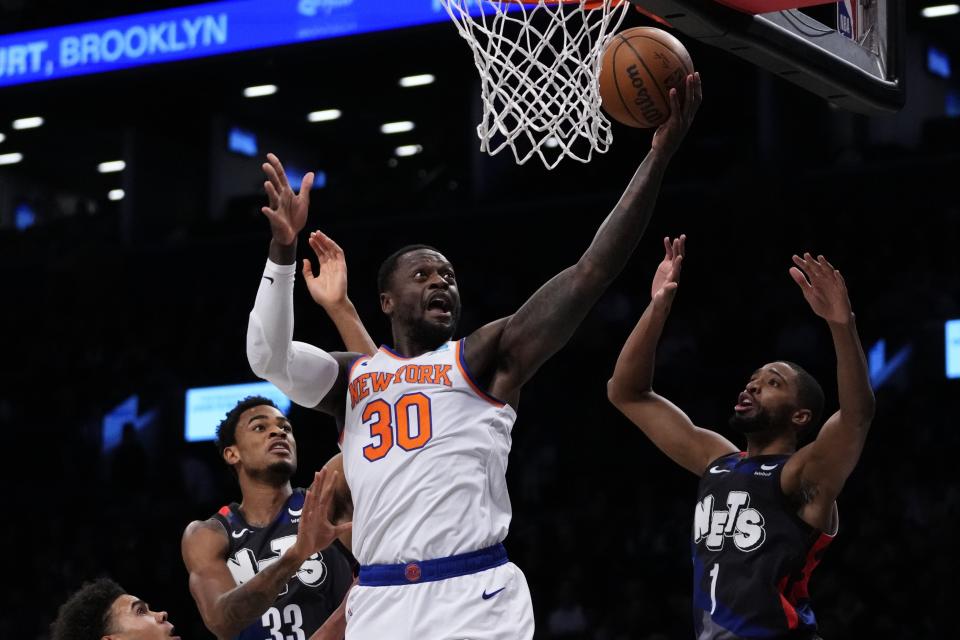 New York Knicks' Julius Randle (30) drives past Brooklyn Nets' Mikal Bridges (1) and Nic Claxton (33) during the first half of an NBA basketball game Wednesday, Dec. 20, 2023, in New York. (AP Photo/Frank Franklin II)
