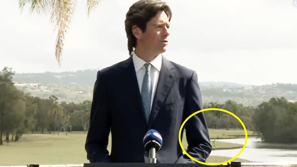 A stubborn golfer looking for his ball behind AFL CEO Gillon McLachlan during a press conference.
