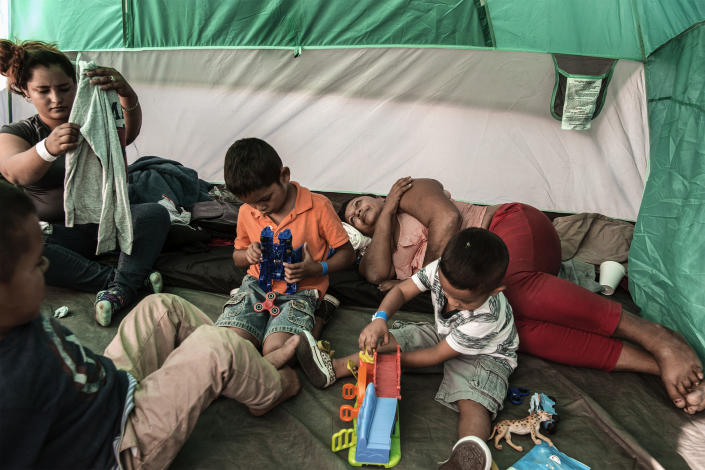 Mirna is resting while Xinia, left, is checking new clothes and Kevin (4), right, Schneider (4) and Oliver (7), left, are playing with games donated by Mexican volunteers at El Barretal shelter in Tijuana on December 2, 2018. (Photo: Fabio Bucciarelli for Yahoo News)