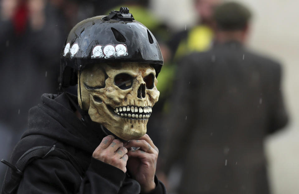 An anti-government demonstrators wears a skull mask and a helmet during a nationwide strike, at Bolivar square in downtown Bogota, Colombia, Thursday, Nov. 21, 2019. Colombia's main union groups and student activists called for a strike to protest the economic policies of Colombian President Ivan Duque government and a long list of grievances. (AP Photo/Fernando Vergara)