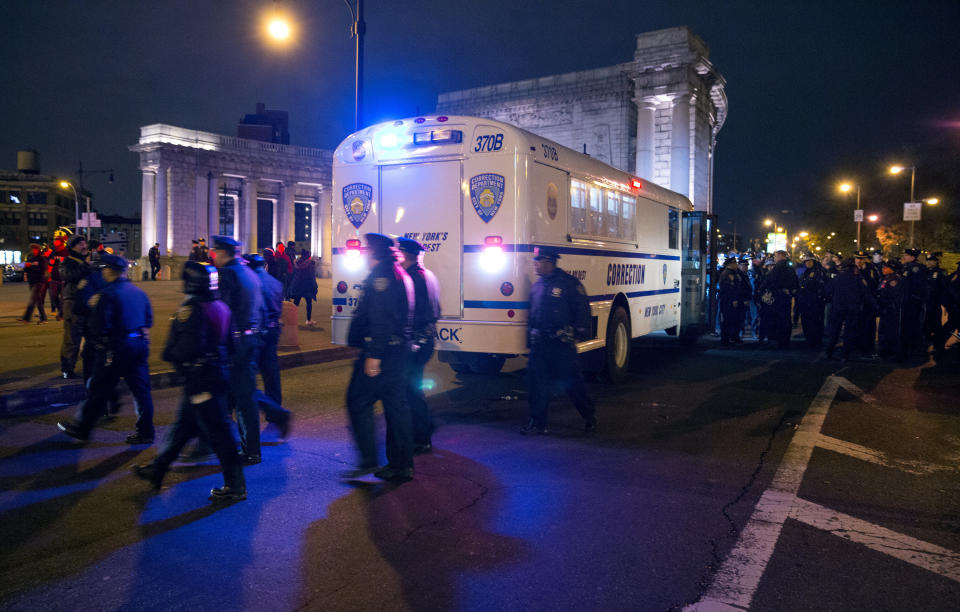 NYPD police officers surround a Department of Corrections bus at the Manhattan side of the Manhattan Bridge Thursday, Dec. 4, 2014, in New York, after several protesters were arrested as they tried to block the bridge entrance protesting against a grand jury's decision not to indict the police officer involved in the death of Eric Garner. A grand jury cleared a white New York City police officer Wednesday in the videotaped chokehold death of Garner, an unarmed black man, who had been stopped on suspicion of selling loose, untaxed cigarettes, a lawyer for the victim's family said. (AP Photo/Craig Ruttle)